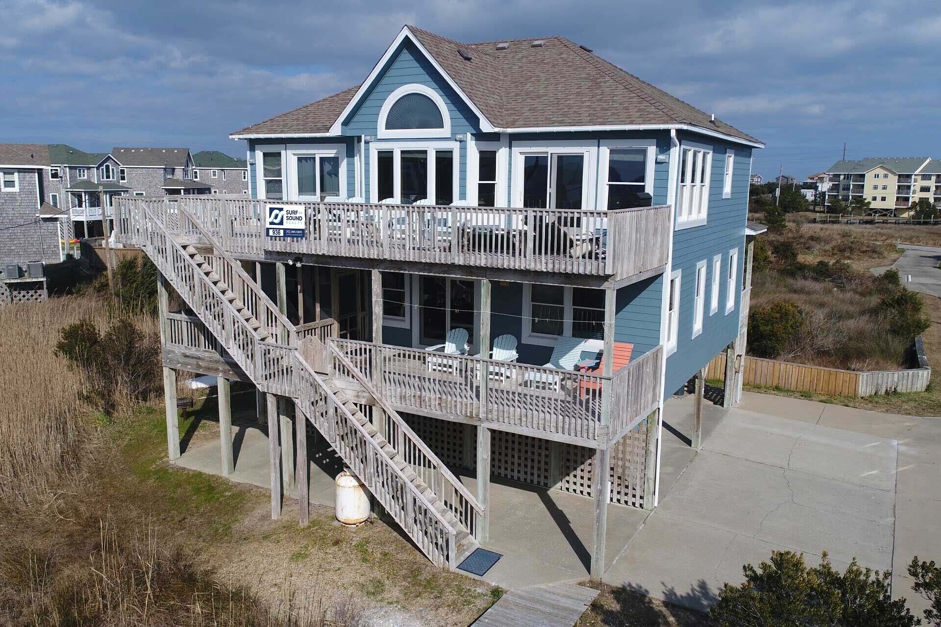A two-story house with a balcony, a wooden staircase, and a view of the surrounding area.