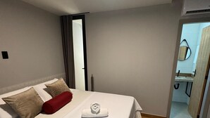 Une chambre à coucher avec un lit, des oreillers, une serviette et un plancher en bois.