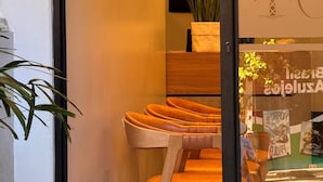 Une chambre d’hôtel avec une chaise en bois, une petite table et une plante en pot.