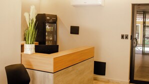 Un comptoir d’accueil avec une machine à café, une plante en pot et une chaise noire.