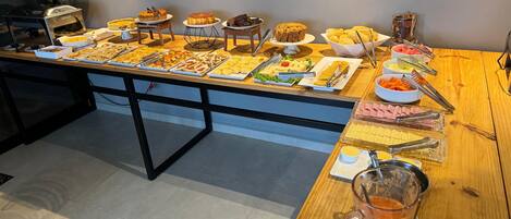 A buffet table with various food items and a pitcher of juice.