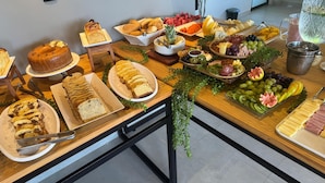 Une table de buffet proposant divers aliments, notamment du pain, des fruits et des fromages.