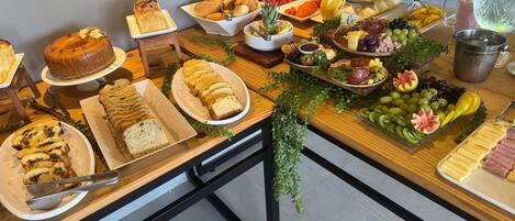A buffet table with various food items including bread, fruits, and cheeses.