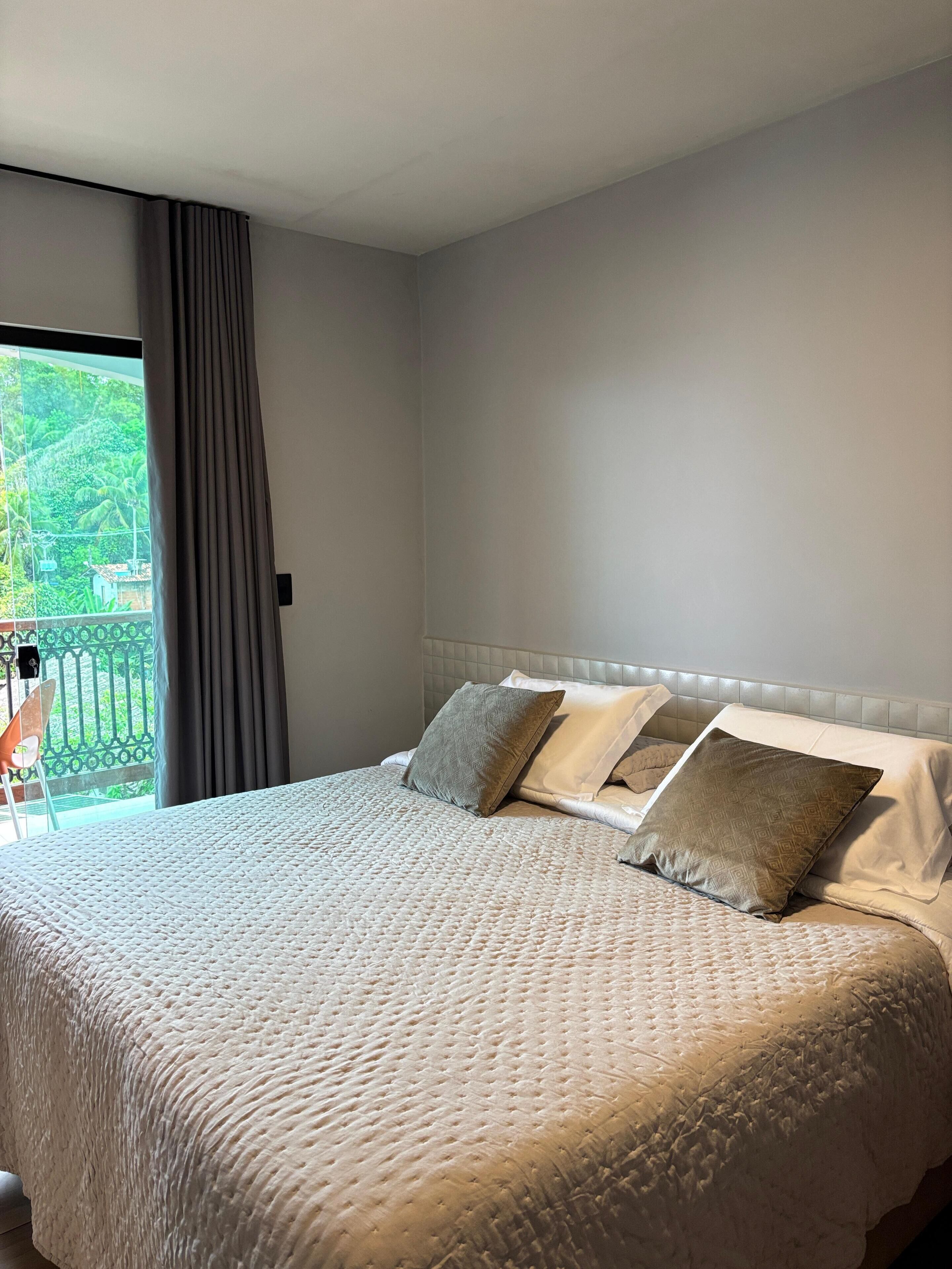 A neatly made bed with a quilted cover, a headboard, and several pillows.
