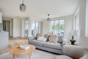 A modern living room with a grey sofa, a wooden coffee table, and a view of a balcony.