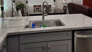 Una cocina moderna con encimera de granito, pileta de acero inoxidable y muebles grises.