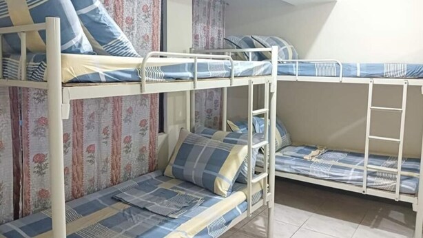Un dormitorio con literas, cortinas estampadas y suelo de baldosas.
