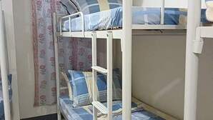 Dormitorio con literas, cortina estampada y suelo de baldosas.