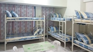 Un dormitorio con literas, una mesita pequeña y sillas.