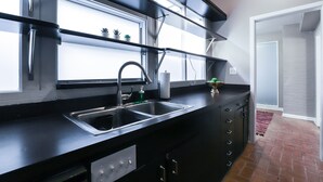 Eine moderne Küche mit schwarzen Arbeitsplatten, Edelstahlgeräten und einem Fenster über der Spüle.