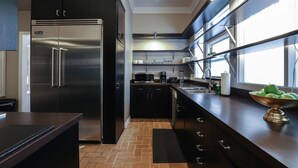 Eine moderne Küche mit Edelstahl-Kühlschrank, schwarzen Schränken, einer Holz Arbeitsplatte und einem Fenster, das für natürliches Licht sorgt.