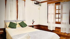 A neatly made bed with a striped blanket, pillows, and a decorative item. - Apartamentos Casa Le Parc (Bocas del Toro)