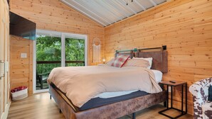 Un dormitorio con paneles de madera, una cama, una mesita y una silla.
