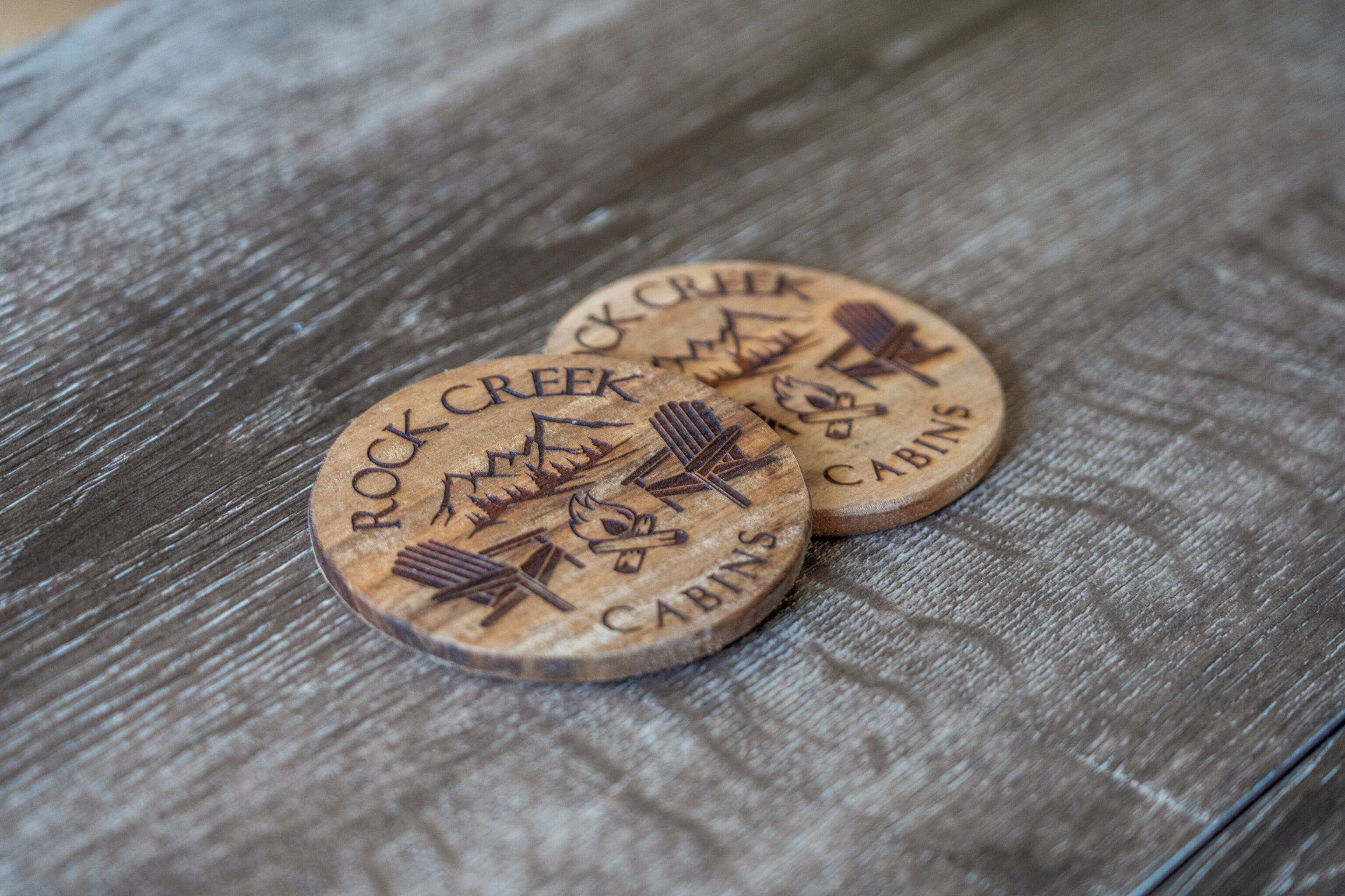 Deux sous-verres en bois portant la gravure « Rock Creek Cabins ».