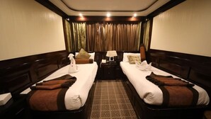 A hotel room with two beds, a nightstand, a lamp, and a curtain. - River Boat - Double Room with Private Bathroom (Cairo)