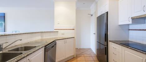A modern kitchen with granite countertops, stainless steel appliances, and white cabinetry.