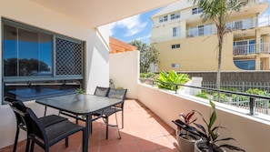 A balcony with a table and chairs, a potted plant, and a view of a building with balconies. - Breakers 1/3- Stone Real Estate Yamba (Yamba)