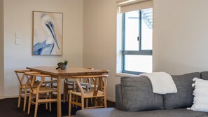 Una habitación con una mesa de comedor y sillas, un sofá gris y una ventana con persianas.