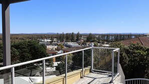 A residential area with a clear view of houses and trees, a balcony with a railing, and a distant mountain range. - Seaspray 8 - Stone Real Estate Yamba (Yamba)
