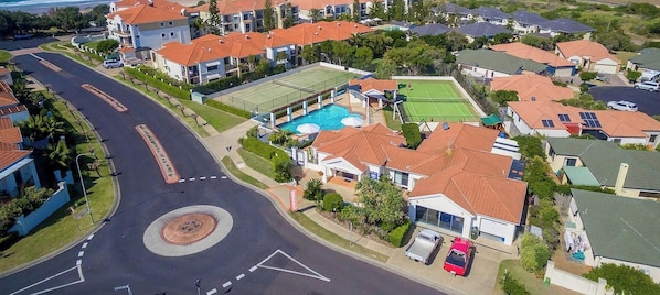 Zona residencial con una glorieta, casas con techos rojos, piscina y canchas de tenis.
