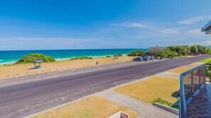 A coastal road with a beach on one side and a parking area with cars.