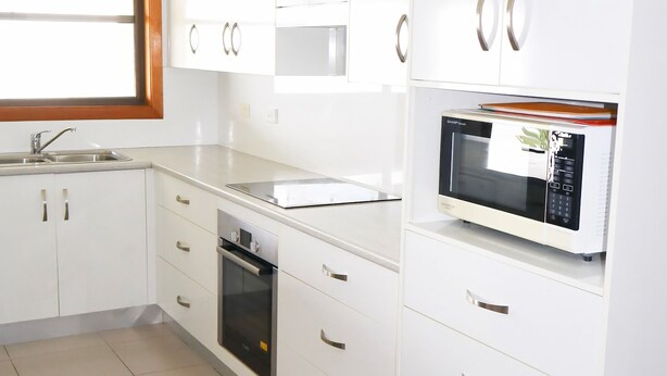 Una cocina moderna con armarios blancos, electrodomésticos de acero inoxidable y un microondas integrado.