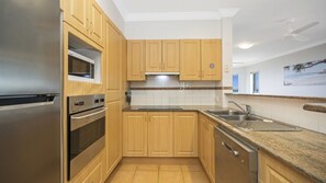 A modern kitchen with wooden cabinets, stainless steel appliances, and a granite countertop.