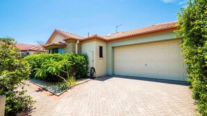 Een woonhuis met garage, verharde oprit en veel groen rondom.