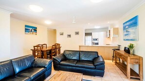 Een knus woongedeelte met een eethoek, een bank, een salontafel en een kitchenette.