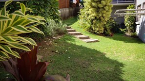 A well-maintained garden with a grassy lawn, a wooden fence, and a series of stone steps leading up to a house.