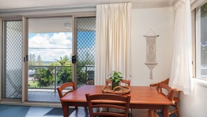 Zona pranzo con tavolo e sedie, una pianta in vaso e vista attraverso una porta scorrevole in vetro.