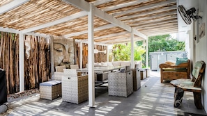 Un patio al aire libre con techo de madera, muebles de mimbre y una gran escultura de piedra.