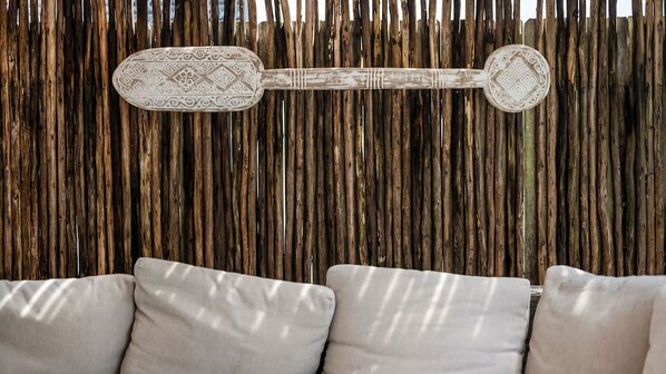 Quarto com parede de bambu trançado e sofá com almofadas.