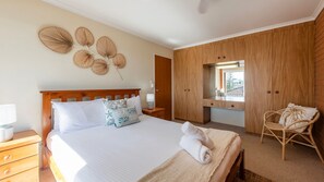 A bedroom with a bed, bedside tables, a chair, a wardrobe, and a wall decoration.