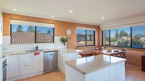 A modern kitchen with white cabinets, a dishwasher, and a large island with a granite countertop.