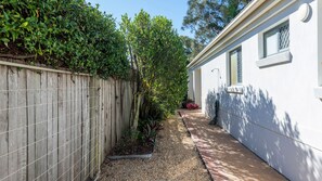 A narrow pathway leading to a white building with a window and a door. - 32 Beachside Way -Stone Real Estate Yamba (Yamba)