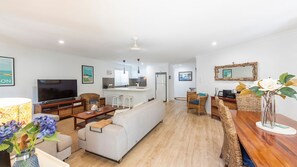A modern living room with a sofa, TV, and dining area. - 32 Beachside Way -Stone Real Estate Yamba (Yamba)