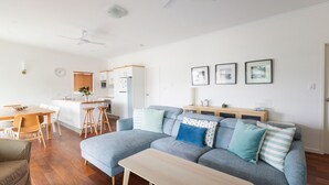 Uma sala de estar moderna com sofá cinzento, mesa de centro de madeira e área de jantar com mesa e cadeiras de madeira.