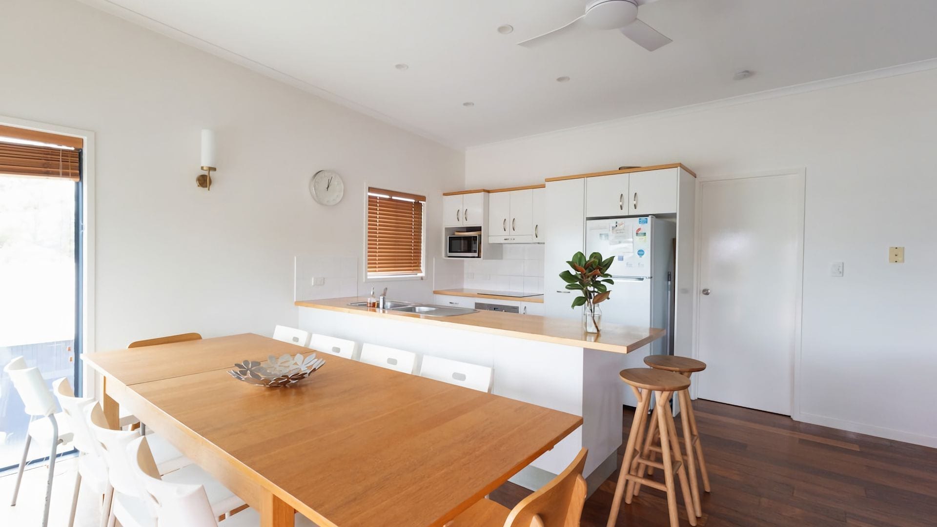 Een moderne keuken met witte kastjes, een houten aanrechtblad en een inbouwmagnetron.