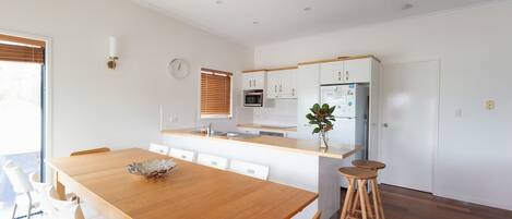 Een moderne keuken met witte kastjes, een houten aanrechtblad en een inbouwmagnetron.