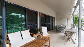 Een modern terras buiten met een houten bank, een eettafel en stoelen.