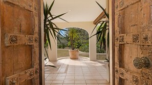 An open wooden door leading to a tiled patio with a potted plant. - Casa Del Rio- Stone Real Estate Yamba (Ashby Heights)