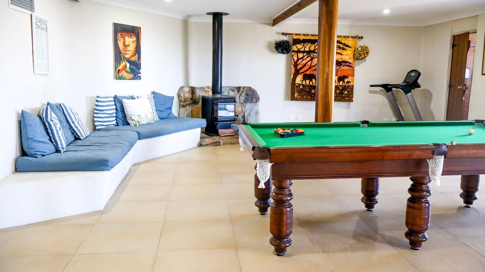 A billiards table in a room with a sofa and a stone fireplace.