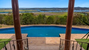 A swimming pool with a view of a river and fields.