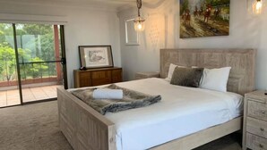 A bedroom with a large bed, a nightstand, a dresser, a framed picture, and a painting on the wall.