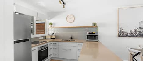 Una cocina moderna equipada con refrigerador, horno, microondas y pileta.