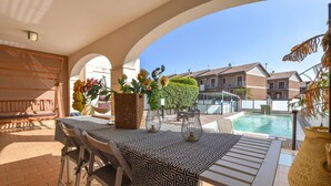 A patio with a pool, outdoor seating, and a view of residential buildings.