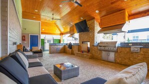 An outdoor living area with a stone fireplace, a grill, and a seating area with sofas and a coffee table. - Dreamy Group-Friendly 2BR | 2Kings w/ BQQ,Gym+Pool (Houston)