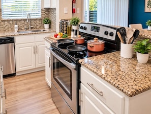 A modern kitchen with stainless steel appliances, granite countertops, and white cabinetry.