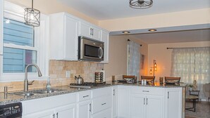 Une cuisine moderne avec des meubles blancs, un four à micro-ondes encastré, une cuisinière à gaz et un lave-vaisselle.